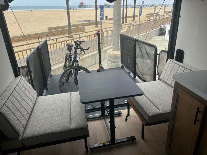 An RV rental with a view! Cozy indoor seating opens to an outdoor deck with a bicycle, scooter, and a sandy beach with a pier.. Forest River Wolf Pup 2025