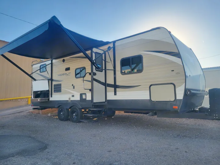 Tan and black Hideout travel trailer RV rental with extended awning & rear outdoor kitchen.. Keystone RV Hideout LHS 2019
