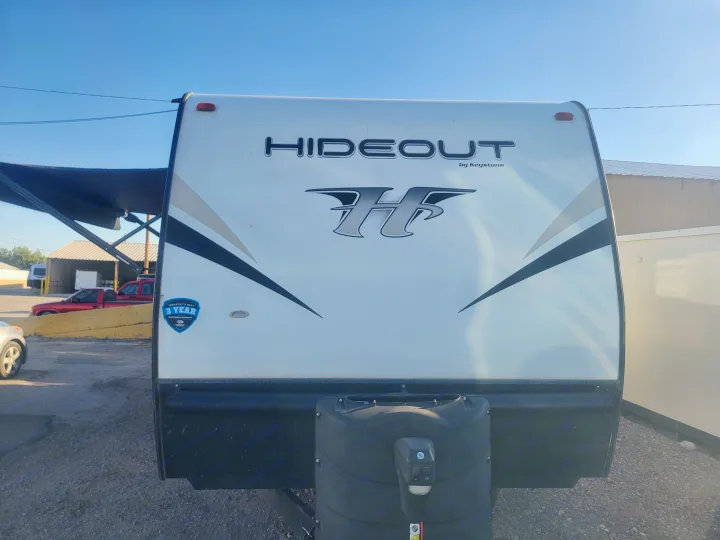 White Hideout by Keystone travel trailer, ideal for rv rental. Front view shows brand, warranty sticker, and propane tank.. Keystone RV Hideout LHS 2019