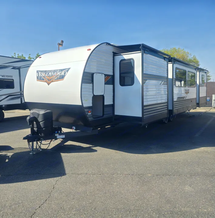 This Forest River Wildwood travel trailer, ideal for an RV rental, is parked outdoors with its slide-out and awning deployed.. Forest River Wildwood 2022