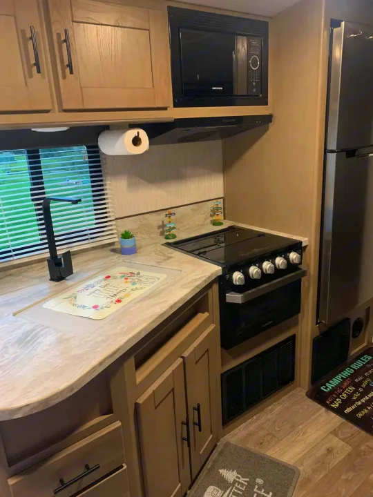 Modern rv rental kitchen with full amenities including stove, microwave, and fridge, perfect for your next adventure.. Heartland RVs Sundance Ultra Lite 2021