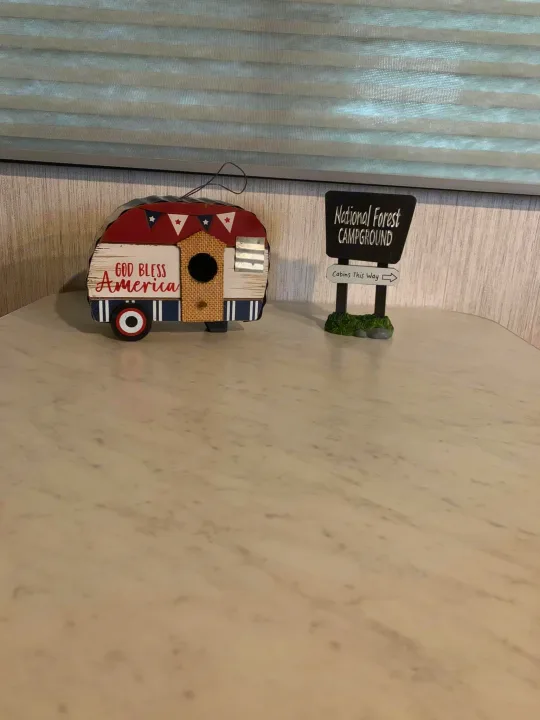 RV rental counter with "God Bless America" camper decor and a "National Forest" campground sign.. Heartland RVs Sundance Ultra Lite 2021
