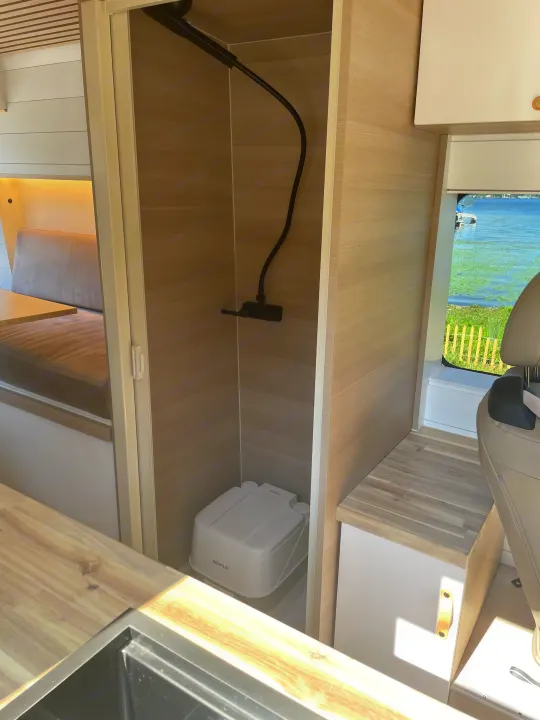 Camper van interior: a compact rv rental with a practical shower, portable toilet, and sleek kitchen area.. Vanberry Promaster 2018