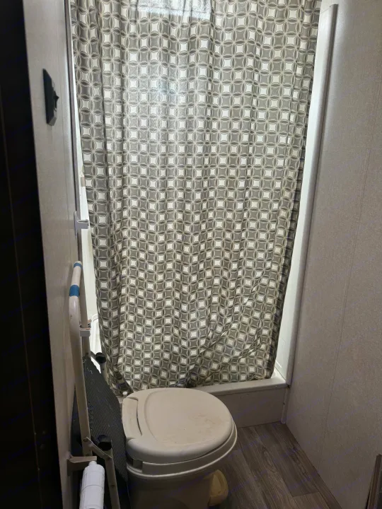 RV rental bathroom featuring a toilet, patterned shower curtain, and a white assistive grab bar.. Jayco Jay Flight SLX Baja Edition 2017