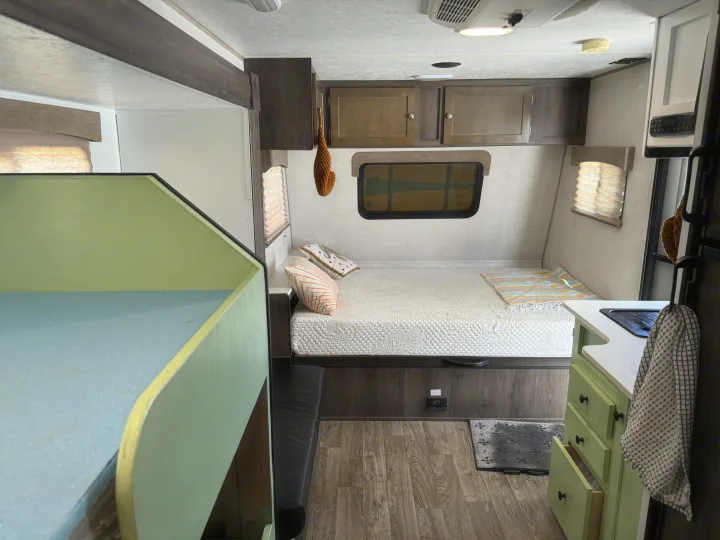 Bright RV rental camper interior with a cozy main bed, bunk beds, and a compact kitchen.. Forest River Viking 2019