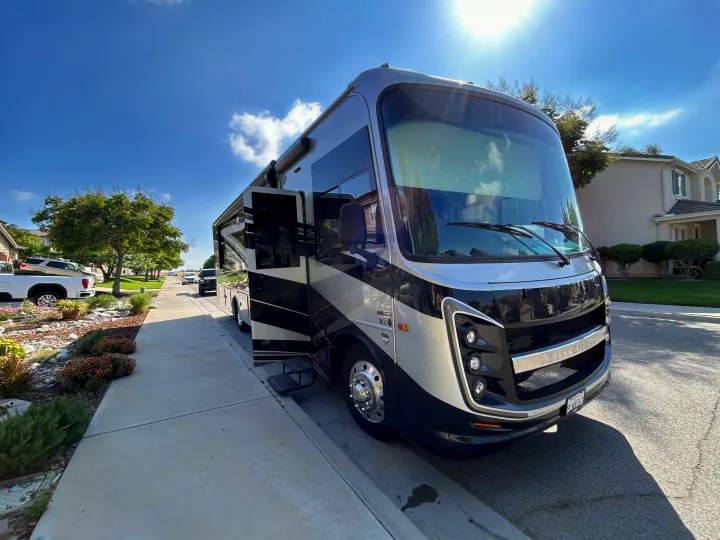 Sleek black and silver RV rental parked curbside on a bright suburban day, door open, perfect for an adventure.. Entegra Coach Other 2024