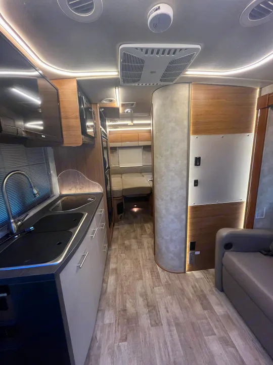 Modern RV rental interior showing a compact kitchen, lounge, and rear sleeping area. Ideal for travel adventures.. Winnebago View 2019