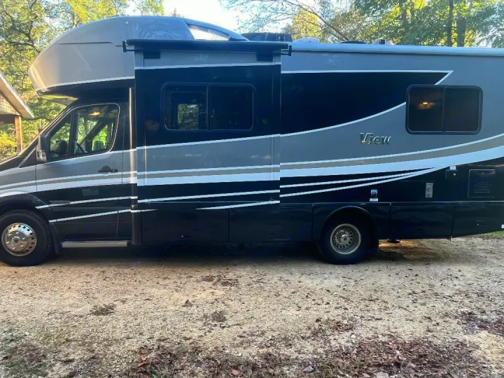 Side view of a black & grey Class C RV on gravel. This 'View' model is a great option for an rv rental.. Winnebago View 2019