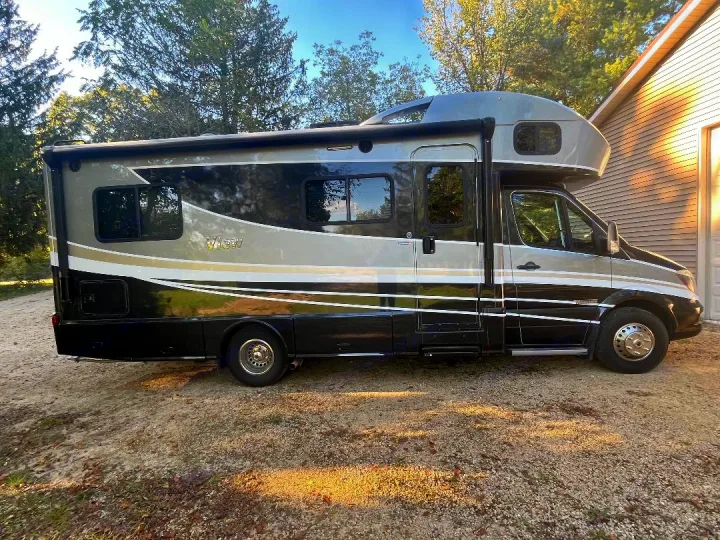 A stylish gray and black motorhome with white accents is parked on a gravel driveway. Perfect for your next RV rental adventure.. Winnebago View 2019
