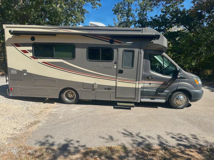 Side view of a grey and cream Winnebago Fuse RV rental parked on asphalt, ideal for your next motorhome adventure.. Winnebago Fuse 2017