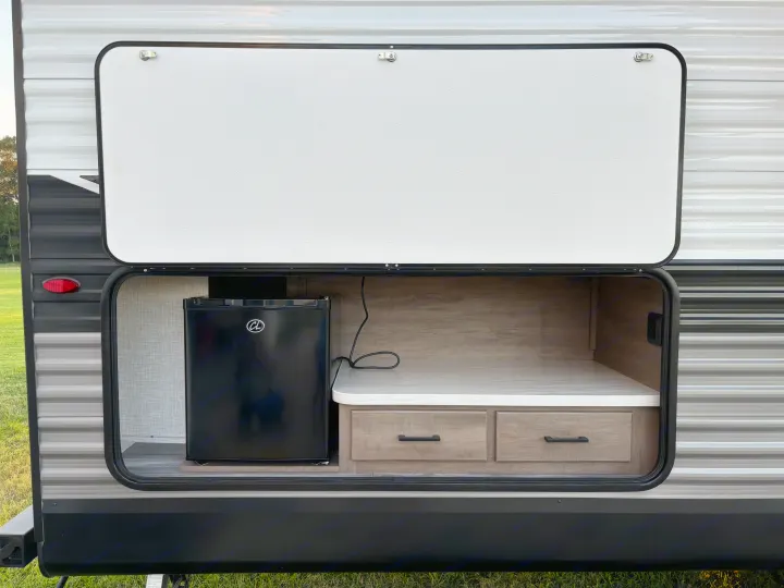 Explore this RV rental's convenient outdoor kitchen, featuring a mini-fridge, countertop, and storage drawers.. Jayco Jay Flight SLX 2024