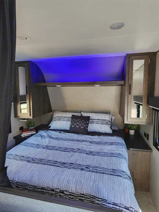 Cozy RV rental bedroom with blue accent lighting, striped bedding, and convenient overhead storage.. Jayco Jay Flight SLX Rocky Mountain Edition 2020