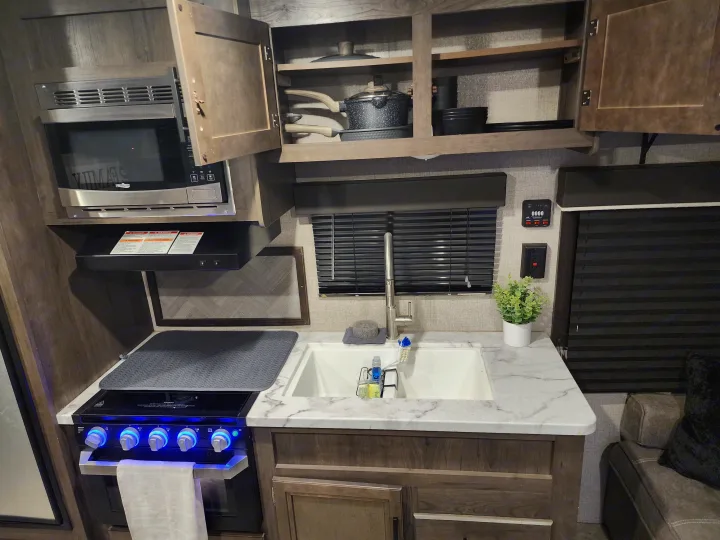 This RV rental features a well-equipped kitchen with a microwave, stove, sink, and open cabinets for road trip cooking.. Jayco Jay Flight SLX Rocky Mountain Edition 2020