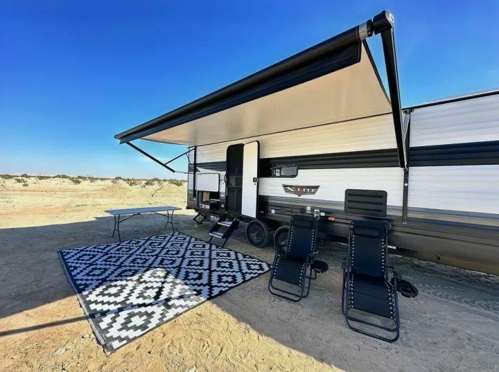 Enjoy your RV rental adventure! Spacious travel trailer with awning, outdoor rug, table, & chairs set up for desert camping.. Forest River Wildwood X-Lite 2024