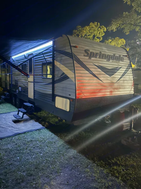 Brightly lit Springdale RV rental at night, with an extended awning. Perfect travel trailer for your campsite.. Keystone RV Summerland 2018