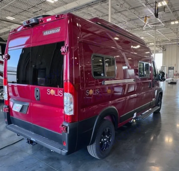 This red Winnebago Solis RV rental van is parked indoors, showcasing its exterior from the rear and side. Ready for adventure.. Winnebago Solis 2023