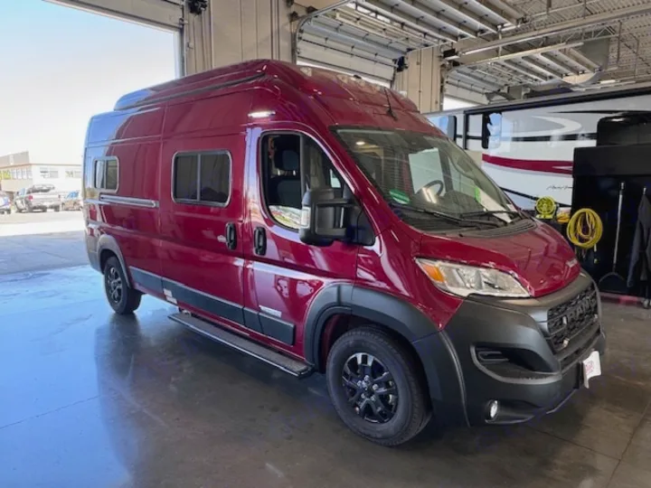 Discover this sleek burgundy camper van, perfect for your RV rental needs. Parked inside, ready for travel.. Winnebago Solis 2023