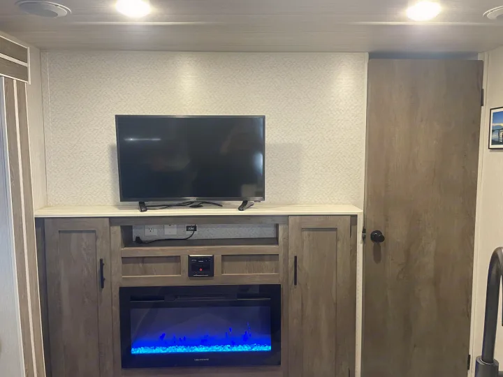 RV rental's modern entertainment area: TV, media console, and an electric fireplace with blue accents.. Forest River Salem Cruise Lite 2022
