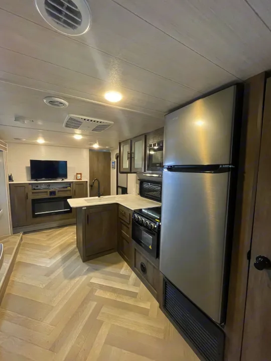 Spacious RV rental interior with modern kitchen, stainless steel appliances, entertainment area, and herringbone floor.. Forest River Salem Cruise Lite 2022