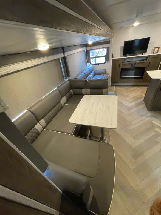 Modern RV rental interior with a spacious U-shaped dinette, entertainment center, and herringbone flooring for comfortable travel.. Forest River Salem Cruise Lite 2022