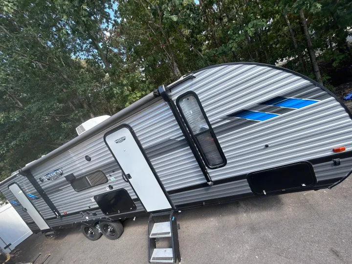 This sleek silver and grey RV rental travel trailer is parked outdoors, featuring steps and an awning.. Forest River Salem Cruise Lite 2022