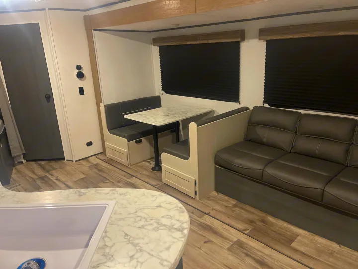 Spacious rv rental interior featuring a bright kitchen counter, dinette, and comfortable sofa, perfect for your next adventure.. Dutchmen 26bhc 2024