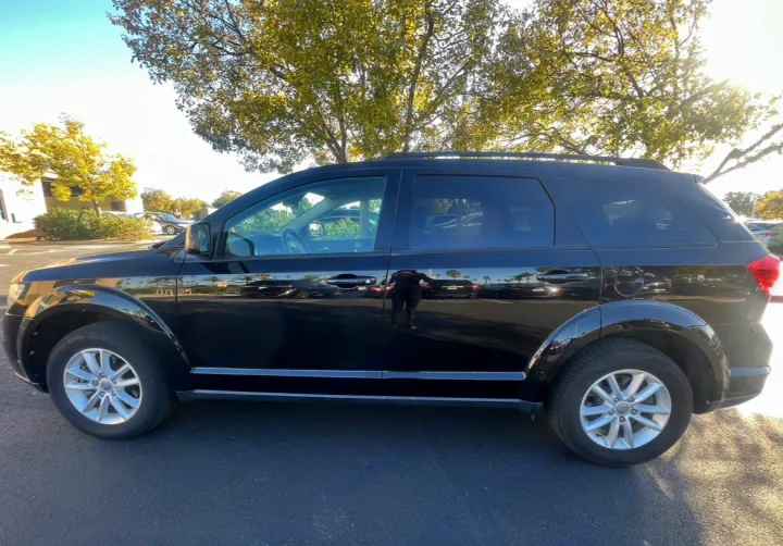 Shiny black SUV parked outside with tree reflections. Great for trips; explore **rv rental** for more adventure.. Dodge Journey 2016
