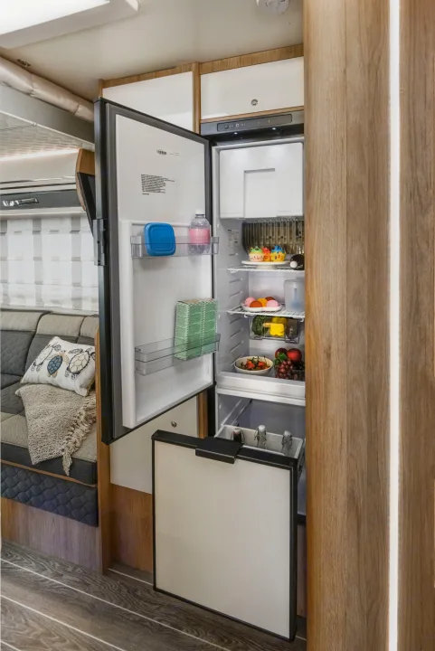 This RV rental features a compact kitchen with an open, well-stocked refrigerator revealing food, drinks, and a pull-out drawer.. Roller Team 707 Auto Roller 2025