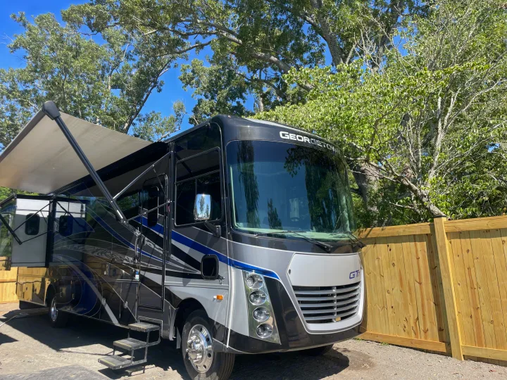 This Georgetown motorhome RV rental, with its awning extended, is parked outdoors next to a new wooden fence.. Georgetown GT7 2022
