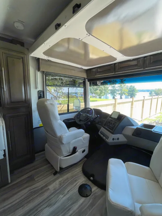 Spacious RV rental interior featuring the driver's area, modern dashboard, and beautiful lake view.. Georgetown GT7 2022