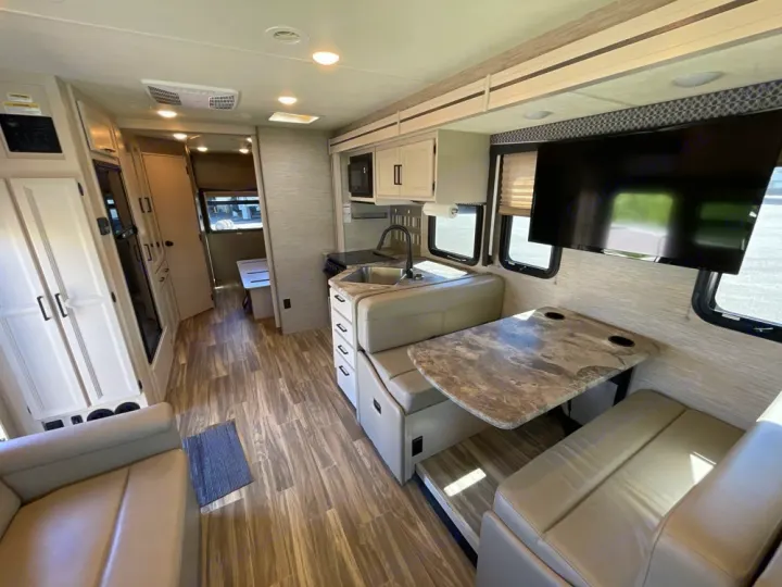 Spacious RV rental interior featuring a modern kitchen, comfortable dinette with TV, and ample living space. Ideal for travel.. Thor A.C.E. 2020