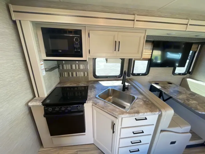 Experience this modern RV rental's interior: full kitchen with microwave, stove, sink, plus a comfy dining booth & TV. Perfect for road trips.. Thor A.C.E. 2020