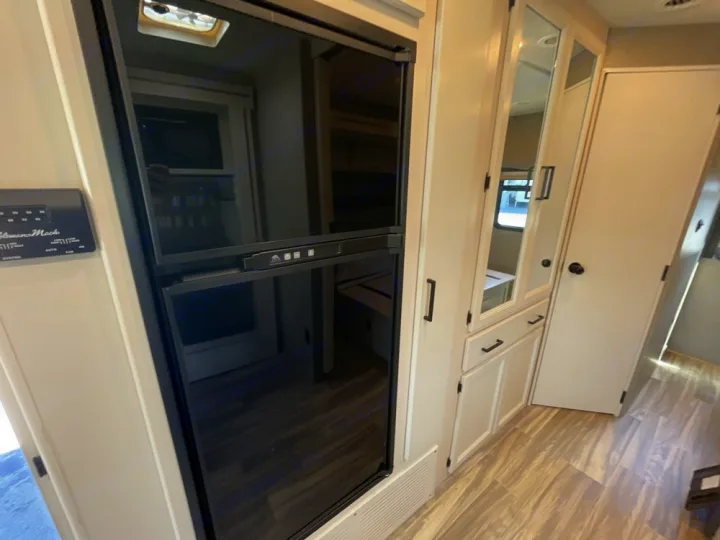 Spacious RV rental interior featuring a modern fridge, mirrored cabinets, and light wood flooring.. Thor A.C.E. 2020