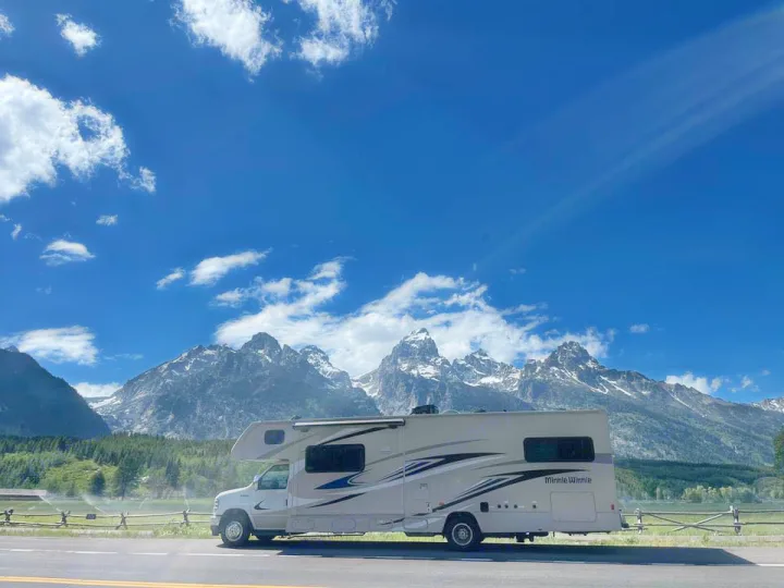 Discover mountain beauty with this Minnie Winnie RV rental, parked roadside with majestic peaks and blue sky.. Winnebago Minnie Winnie 2021