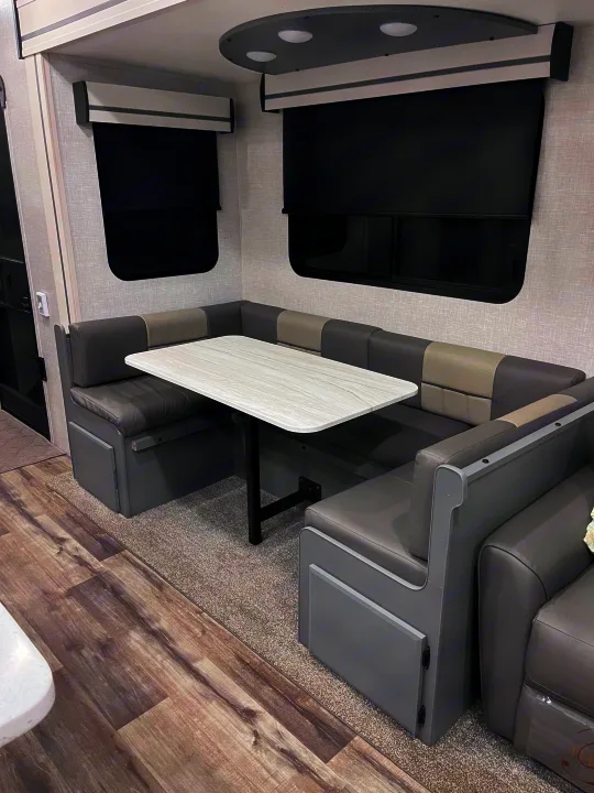 Inside an RV rental: a spacious dinette area featuring U-shaped seating, a table, and dark window blinds.. Volante 375MD 2023
