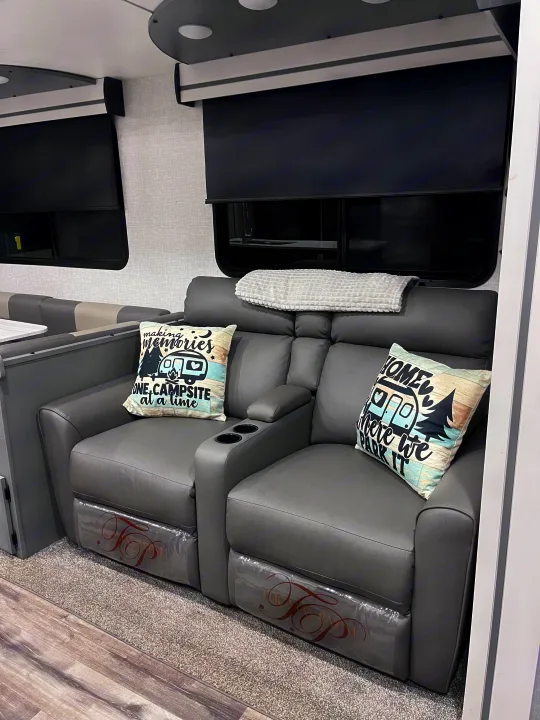 Cozy RV rental interior: grey recliners with cupholders, themed pillows, and blackout shades for comfortable travel.. Volante 375MD 2023
