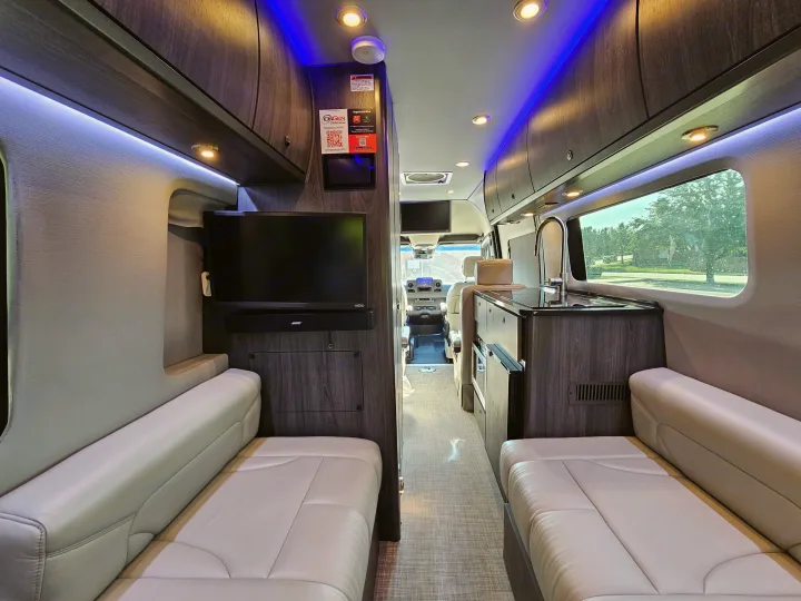 Plush RV rental interior showcasing a modern living space with beige seating, dark wood cabinets, and blue accent lights.. Grech Strada Ion 2022