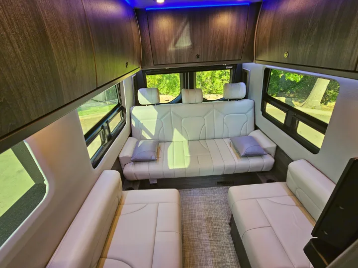 Luxury RV rental van interior featuring cream leather seating, overhead cabinets, and blue LED lighting. Spacious and modern.. Grech Strada Ion 2022