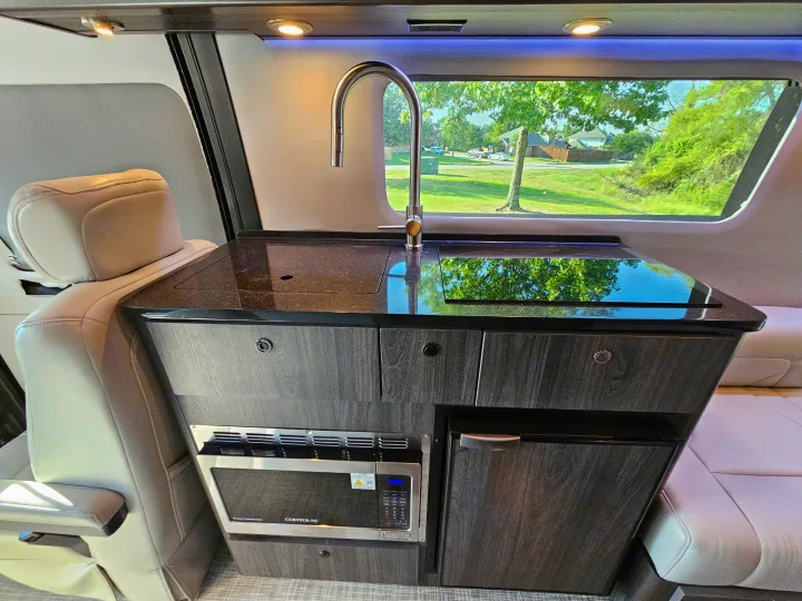 Tour this RV rental's modern interior. A full kitchenette with sink, microwave, cooktop, and fridge offers convenience for travel.. Grech Strada Ion 2022