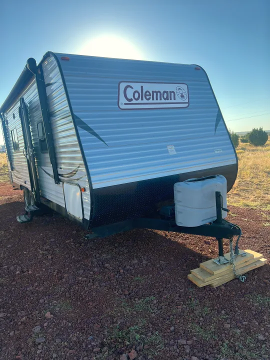 Sunny outdoor shot of a Coleman travel trailer, perfect for RV rental. Parked on dark gravel, ready for adventure.. Dutchmen Coleman Lantern LT 2016
