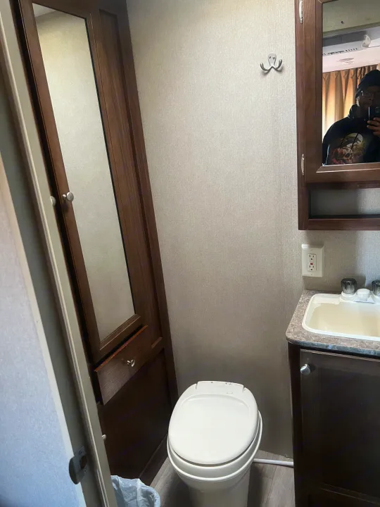 RV rental bathroom with a compact toilet, sink, vanity, and mirrored cabinet, efficiently designed for travel.. Dutchmen Coleman Lantern LT 2016