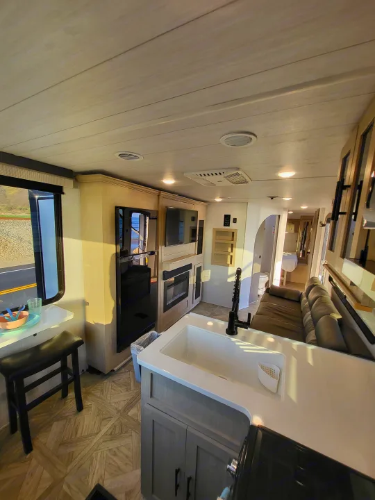 Explore this modern RV rental interior, showcasing a bright kitchen, cozy living area with TV, and dining nook.. Forest River Wildwood 24 view 2024
