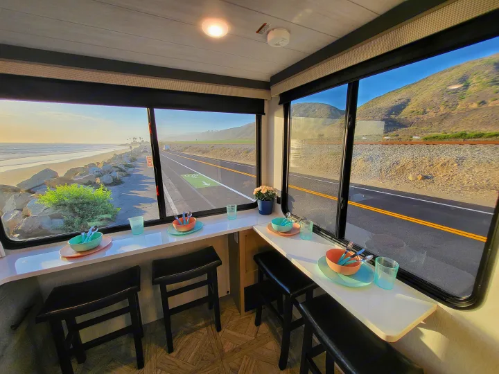 Breathtaking panoramic views from your RV rental's dining area, overlooking a scenic coastal road and ocean.. Forest River Wildwood 24 view 2024