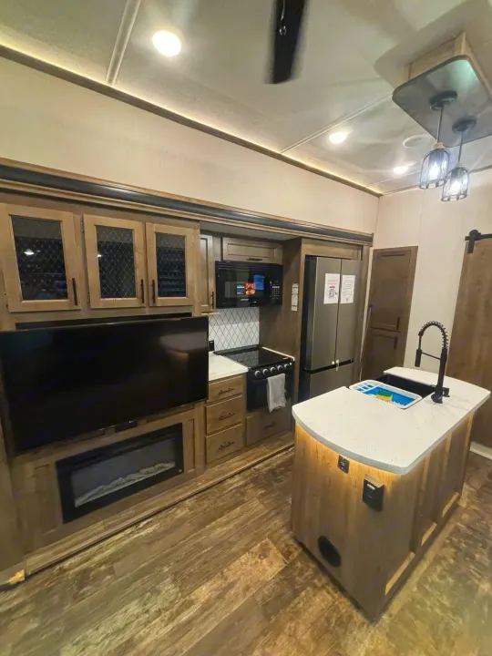 Modern RV rental interior: Full kitchen, living area with TV/fireplace. Perfect for cozy travels.. Forest River Sabre 2022