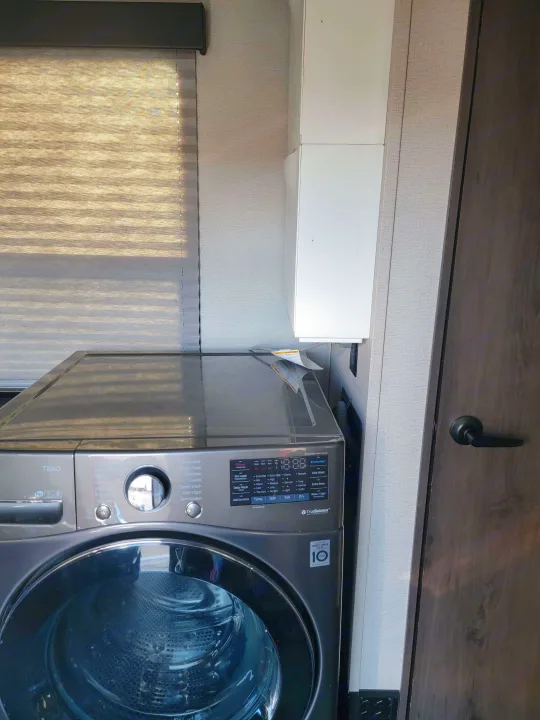 An LG front-load washing machine is shown inside a compact RV rental, providing convenient laundry on the go.. Grand Design Momentum 2022
