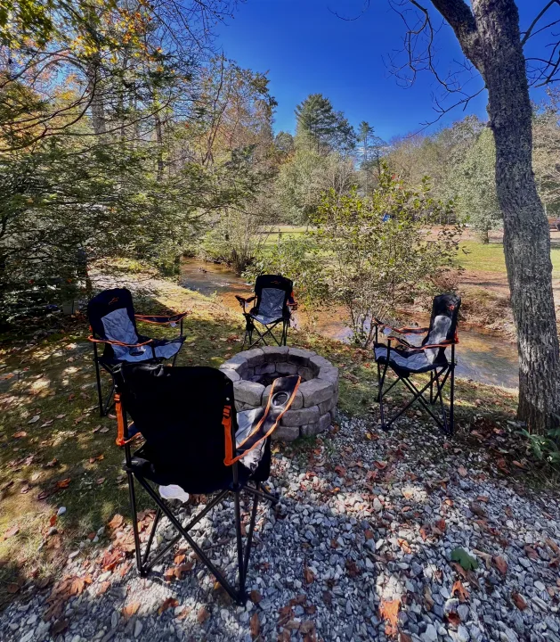 Campsite bliss: Stone fire pit & chairs by a stream, ideal for an RV rental getaway. Enjoy nature's peace.. Jayco Envoy 100 2018