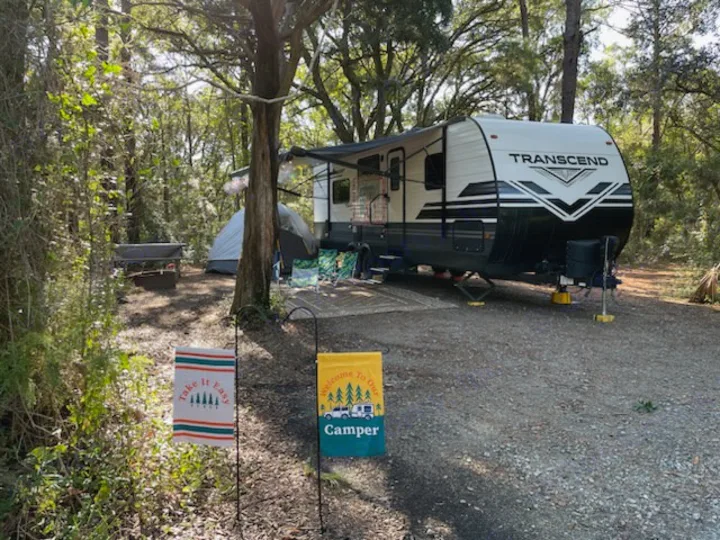 Enjoy this scenic rv rental campsite with a large RV, tent, and cozy fire pit area, surrounded by lush nature.. Grand Design Transcend Xplor 2021