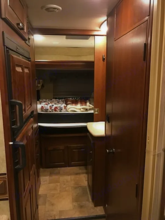 RV rental interior with a compact fridge, tiled floor hallway, and a cozy bedroom area visible beyond.. Forest River Solera 24R 2014