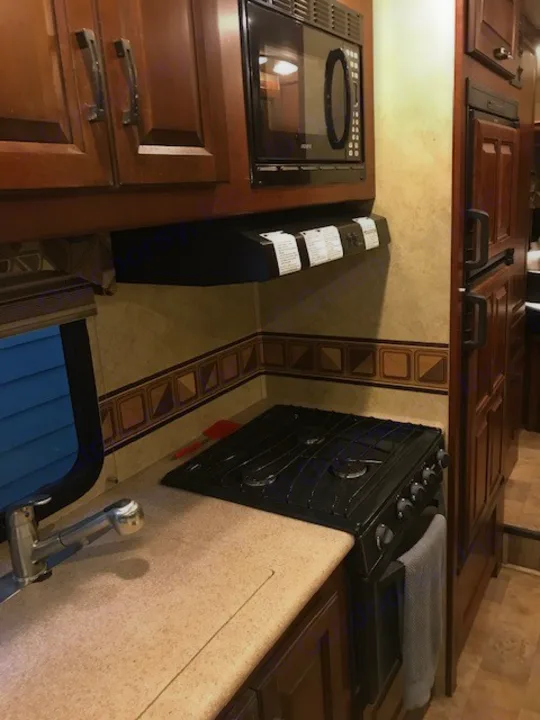 Explore an RV rental's compact kitchen featuring a microwave, cooktop, oven, and sink, designed for travel.. Forest River Solera 24R 2014