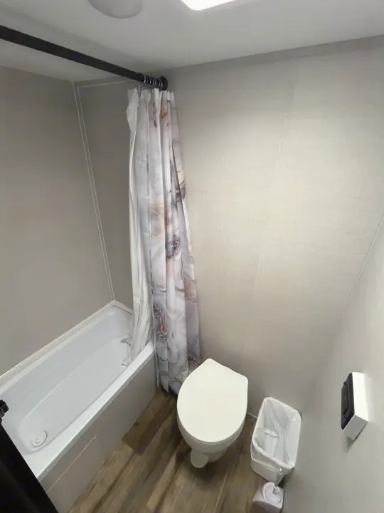 Clean RV rental bathroom featuring a shower/tub combo, toilet, and patterned curtain.. Gulf Stream grand river 2024